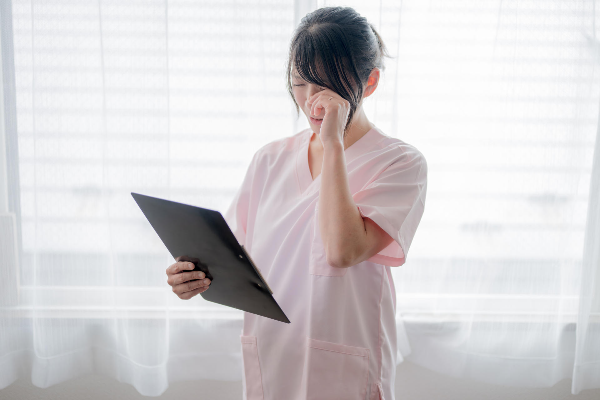目をこする辛そうな介護職の女性