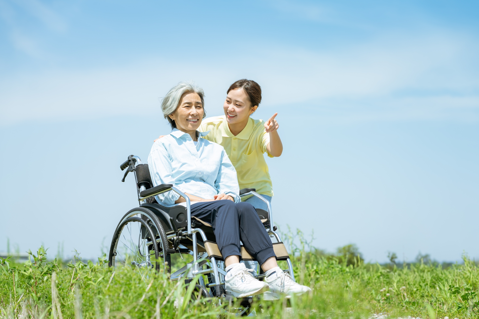 遠くを指差す女性と車椅子の女性