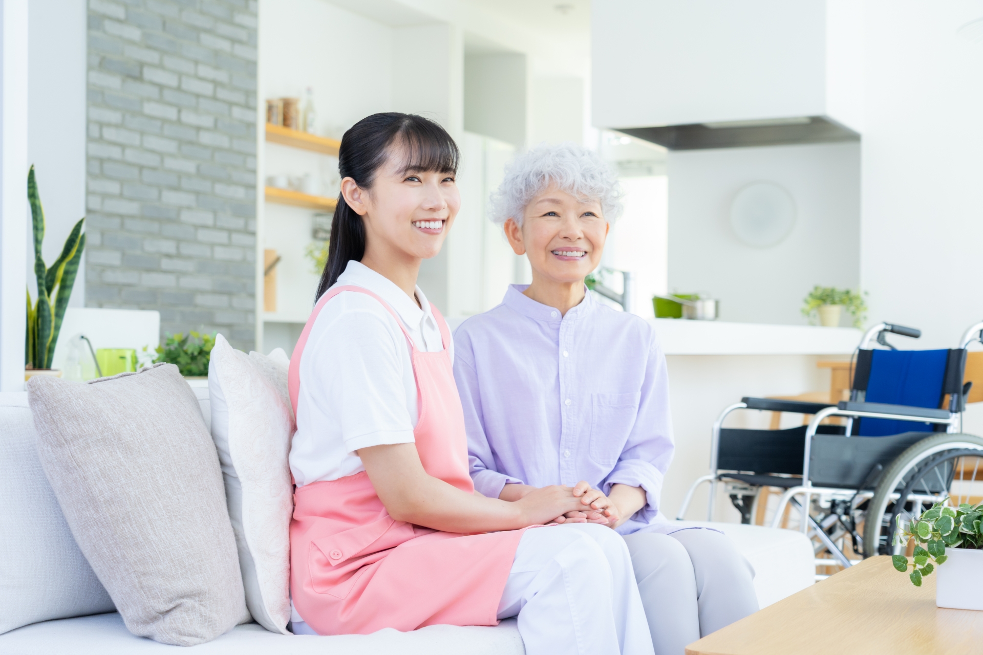 ソファに座る高齢女性とエプロンの女性