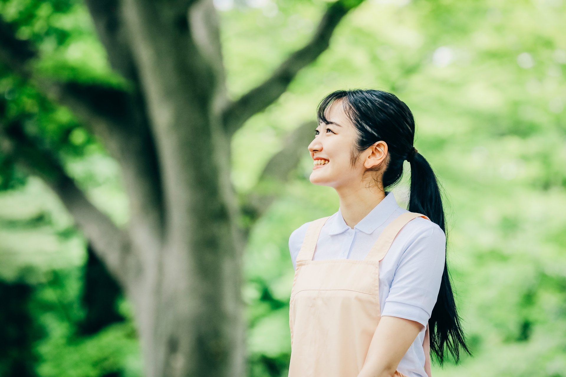 屋外を笑顔で歩くエプロンの女性