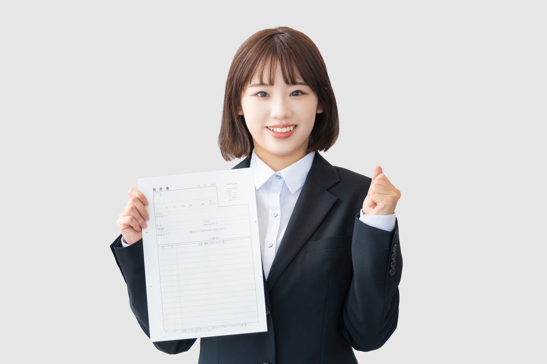履歴書を持ってガッツポーズするスーツの女性