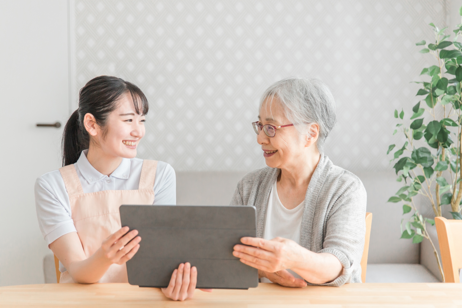 タブレットを見る高齢女性と介護士