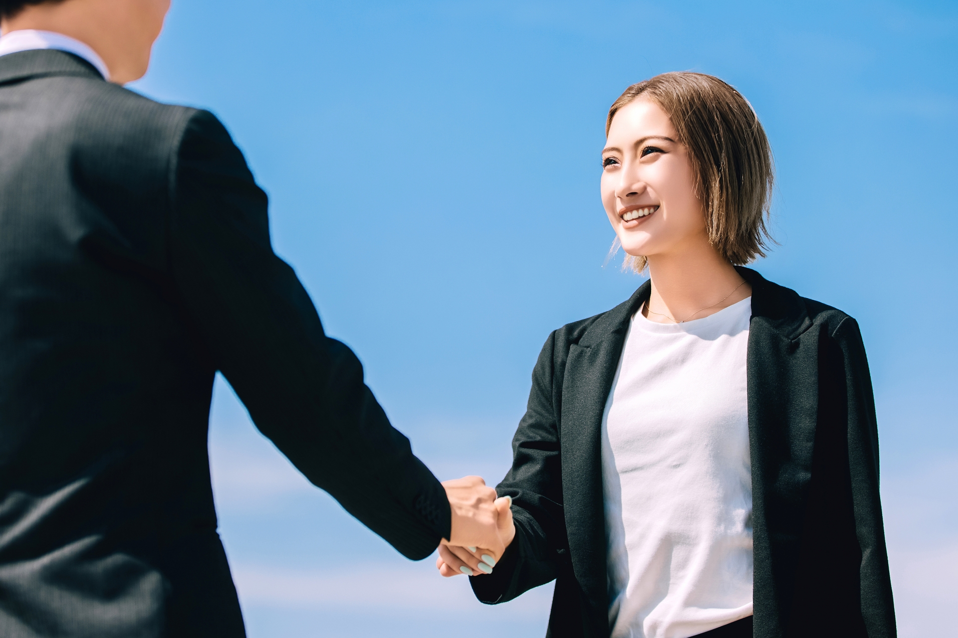 笑顔で握手をする男女のビジネスマン
