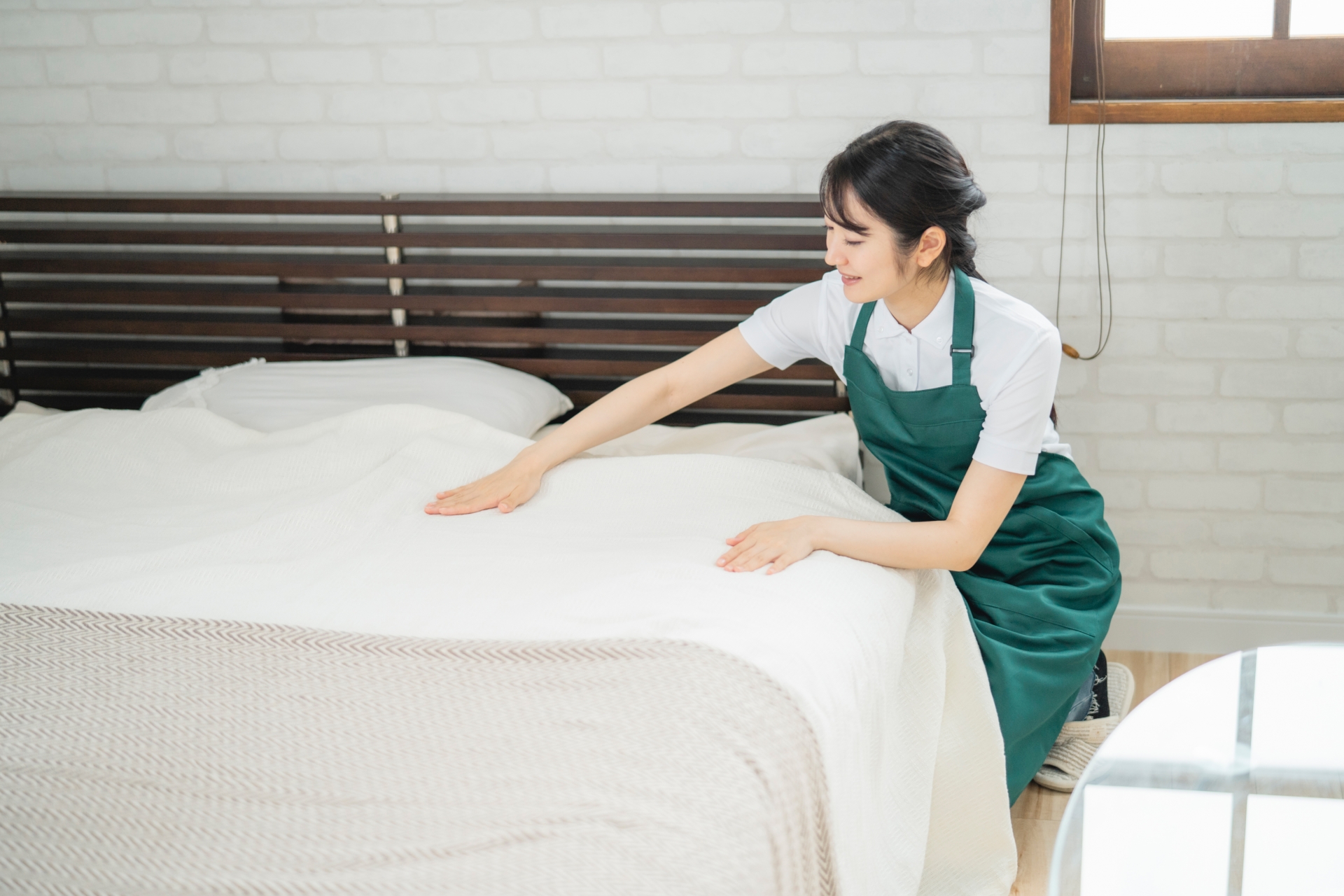 ベッドメイキングする女性