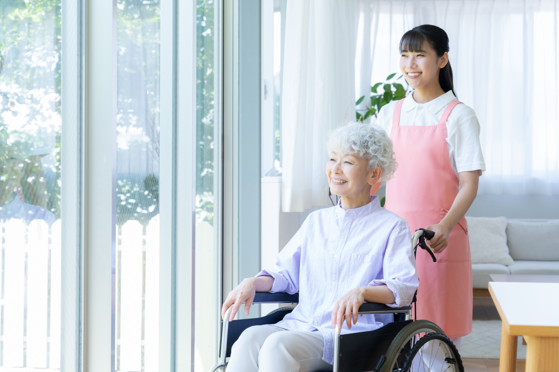 窓の外を見る介護士と車椅子の女性