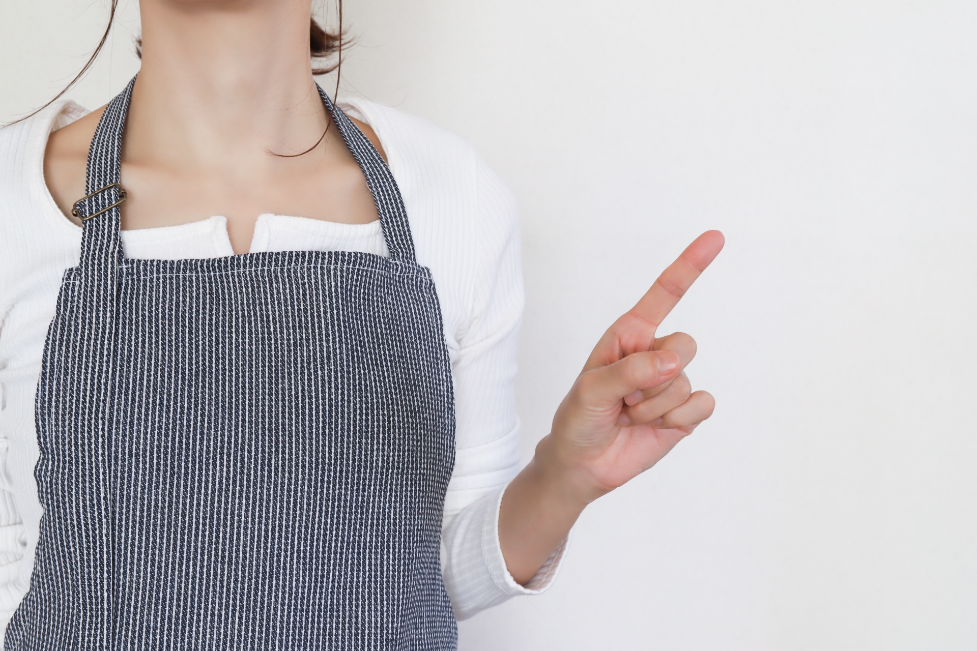 人差し指を立てるエプロンの女性