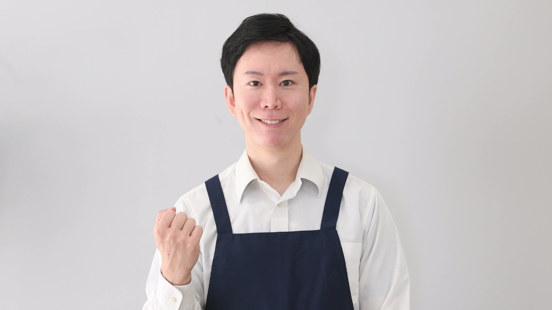 ガッツポーズするエプロンの男性