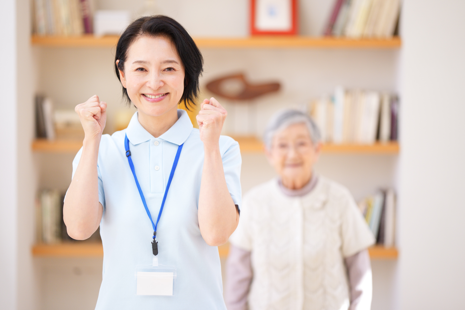 ガッツポーズしている介護士の女性と高齢女性