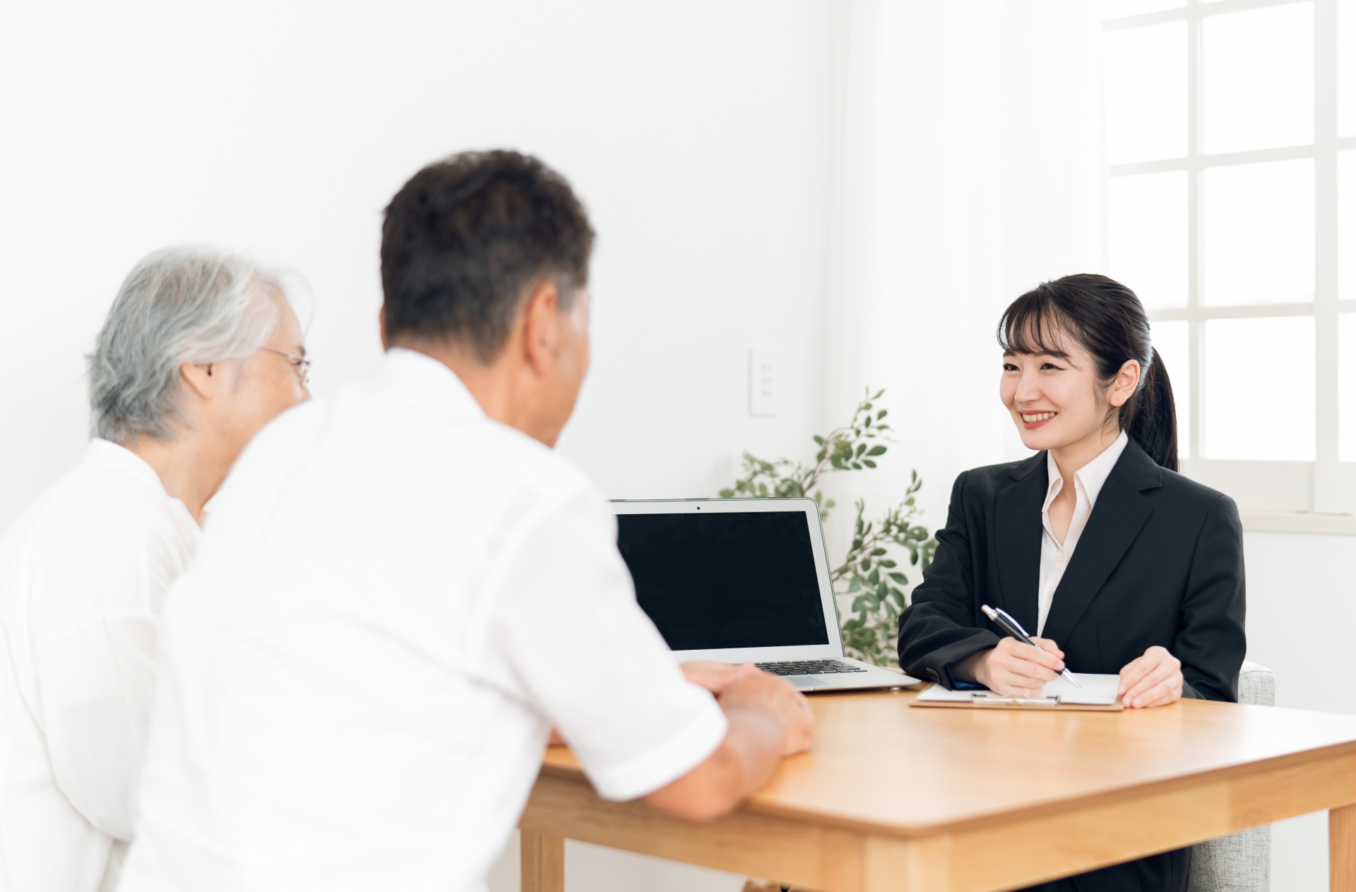 パソコンで説明するスーツ姿の女性と夫婦