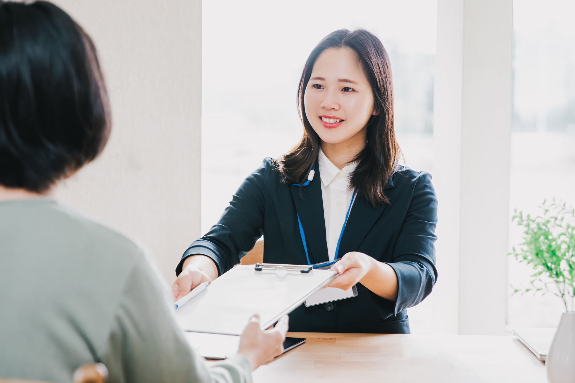 バインダーを差し出す受付の女性