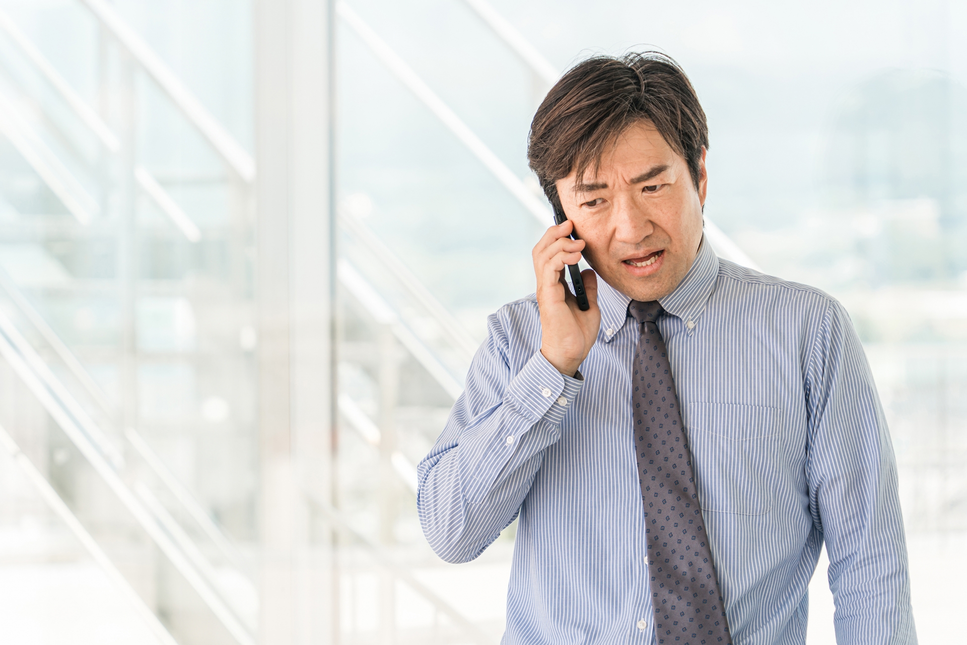 険しい顔で電話する男性