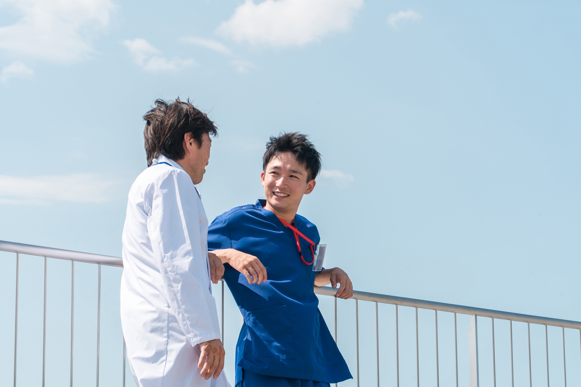 青空の下で会話する男性同士