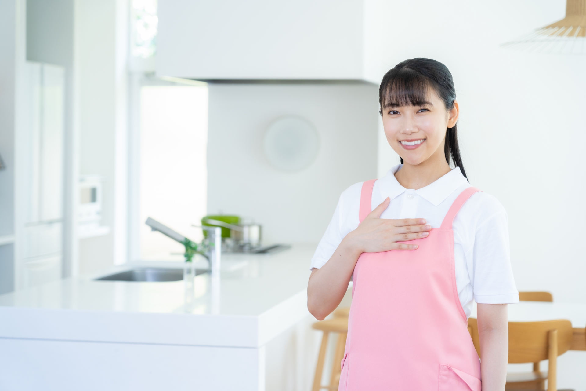 胸に手を当てるエプロンの女性
