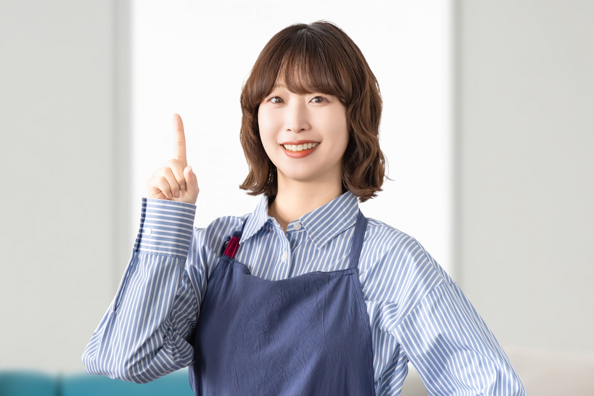 人差し指を立てて案内するエプロン姿の女性