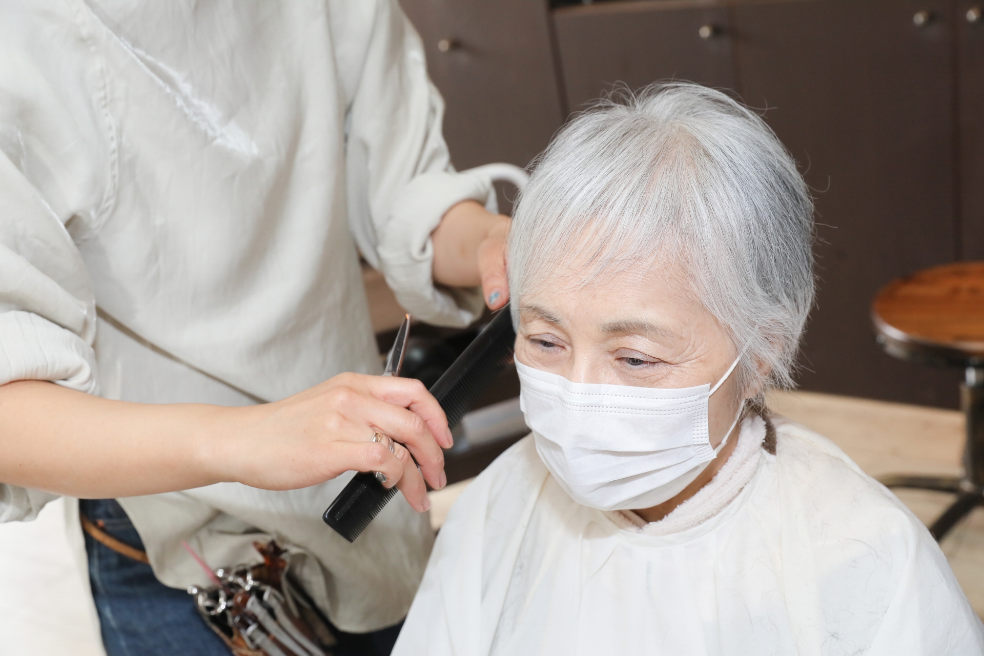 ヘアカットする美容師と高齢者女性