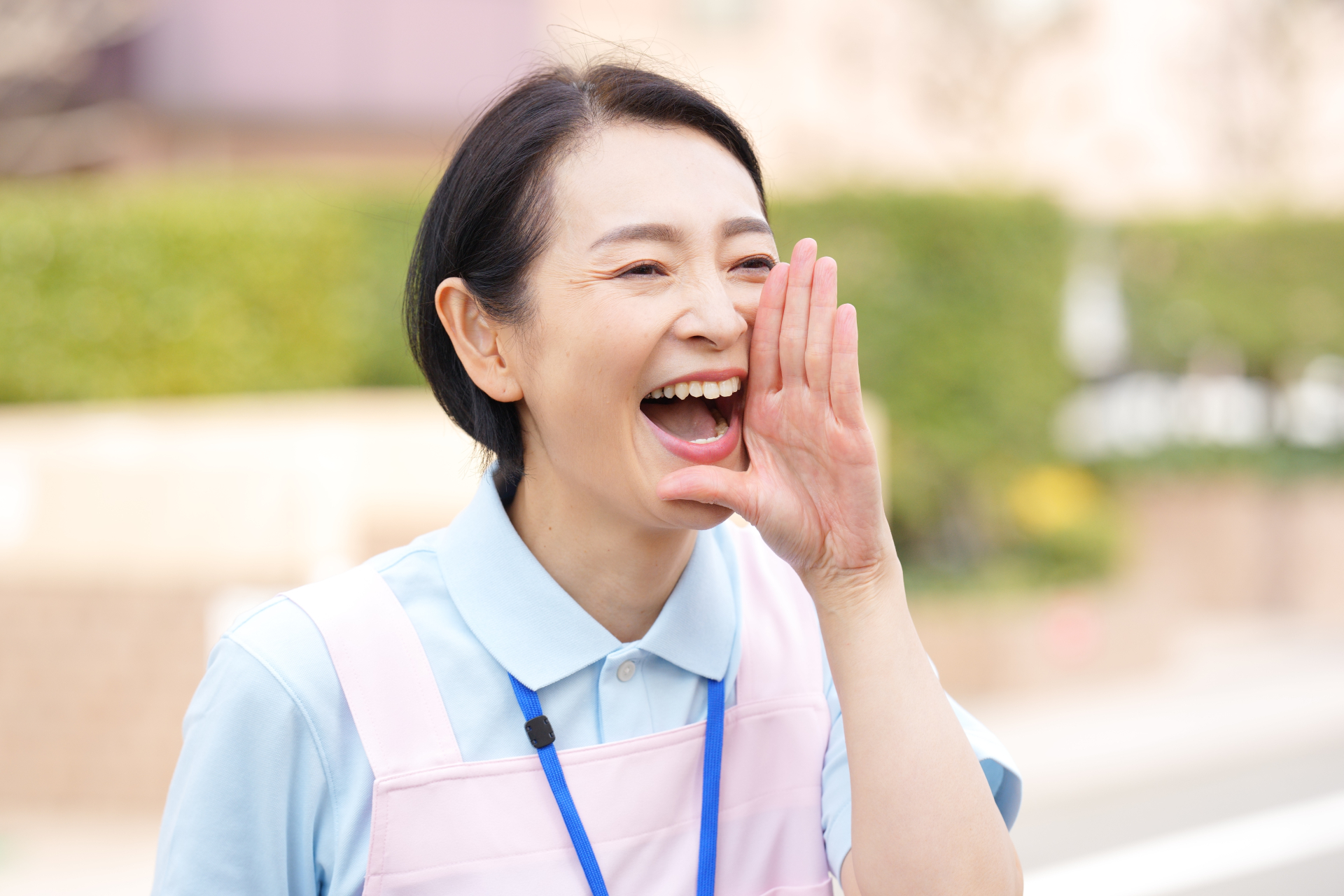 屋外で呼びかける笑顔の女性介護士