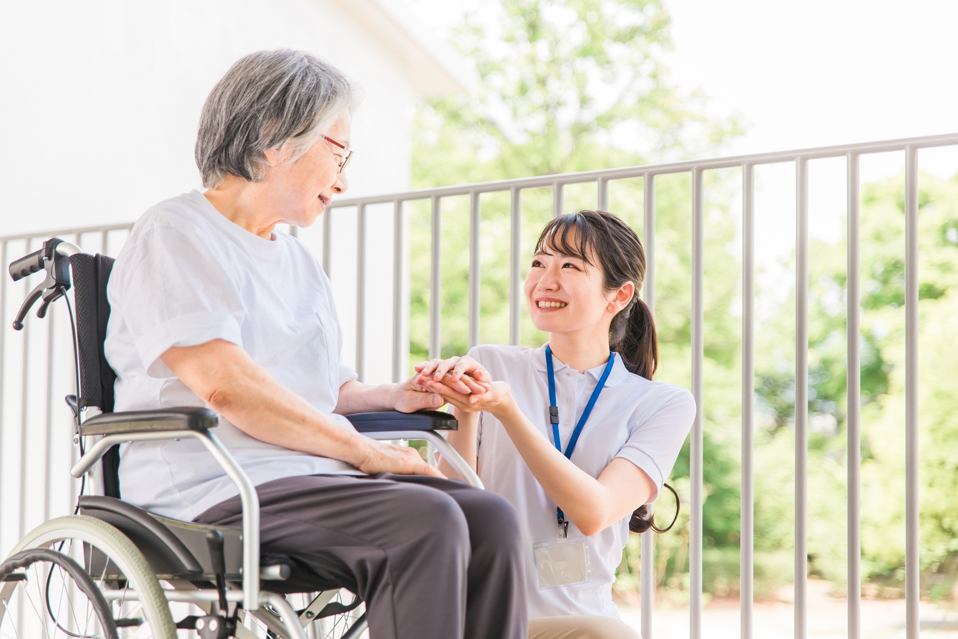 車椅子の女性とそばで座る介護士