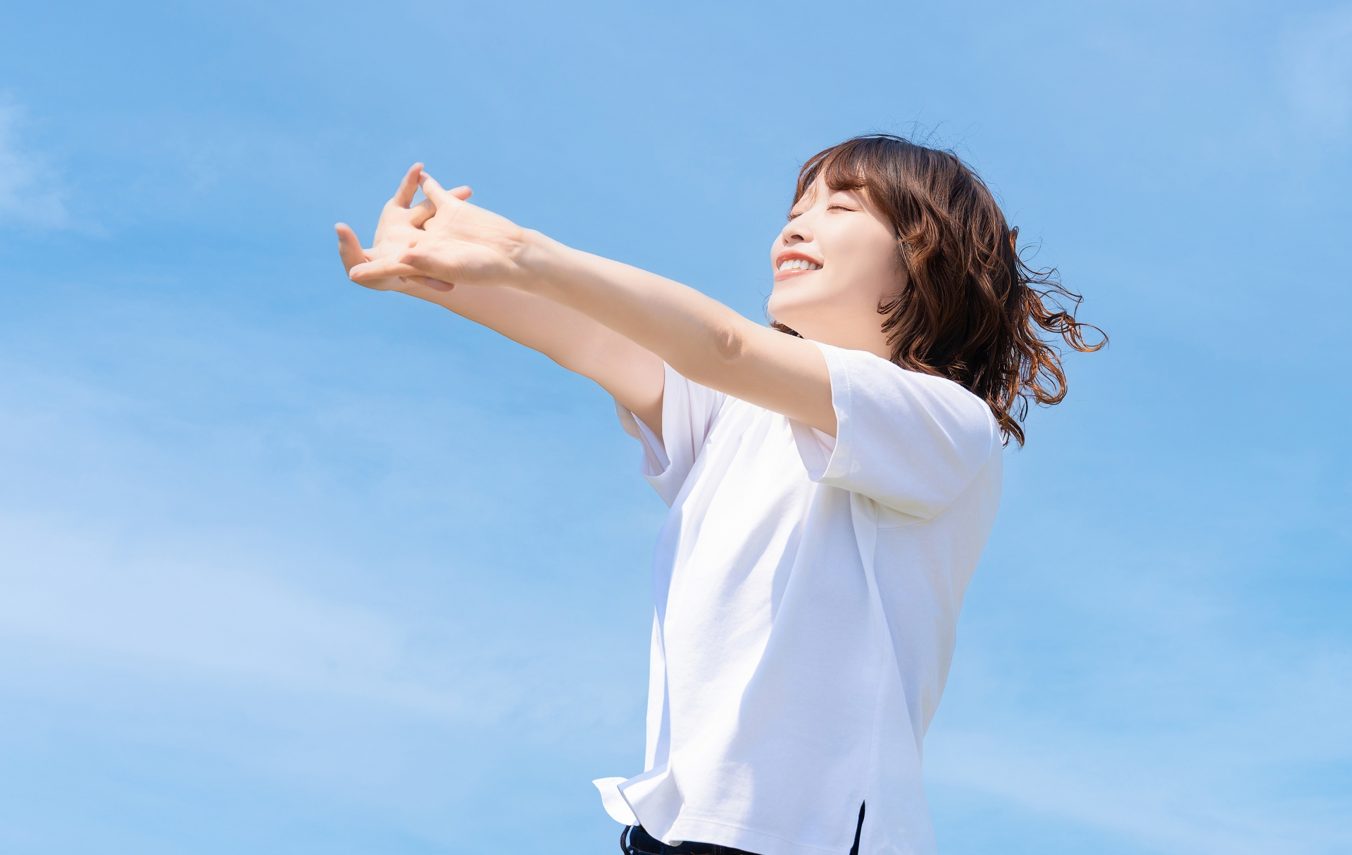夏の青空とストレッチをする笑顔の女性