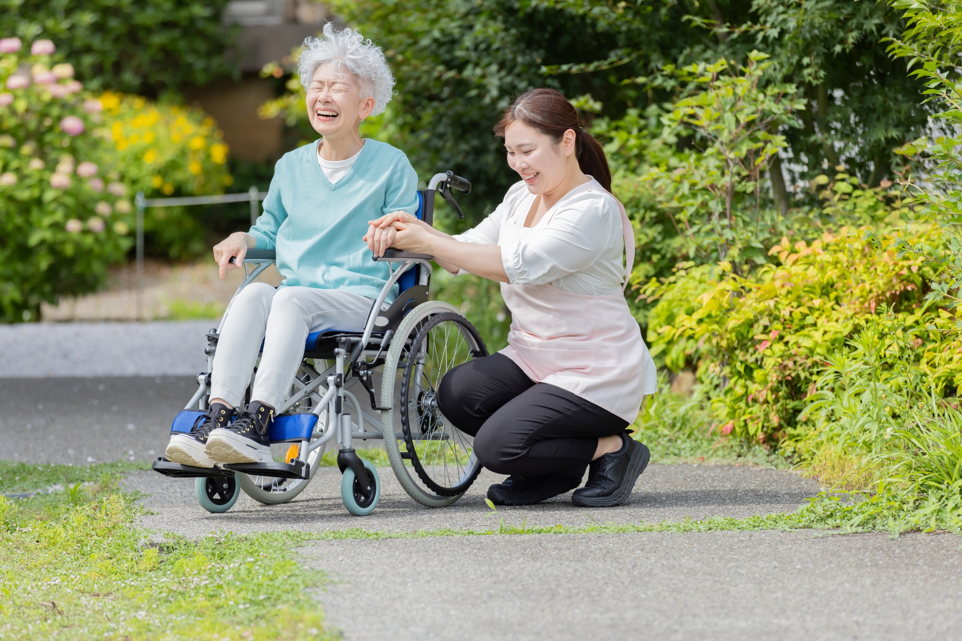 車椅子に乗るシニア女性とヘルパー