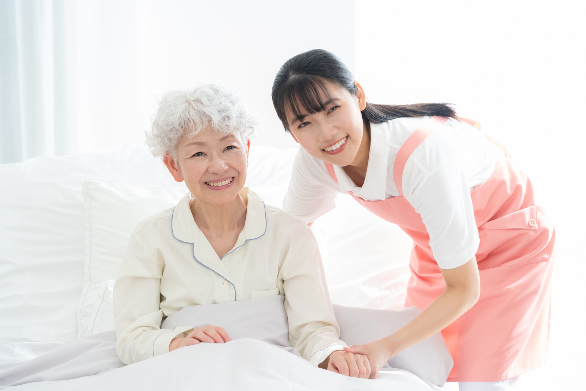 ベッドにいる高齢者に寄り添う介護士