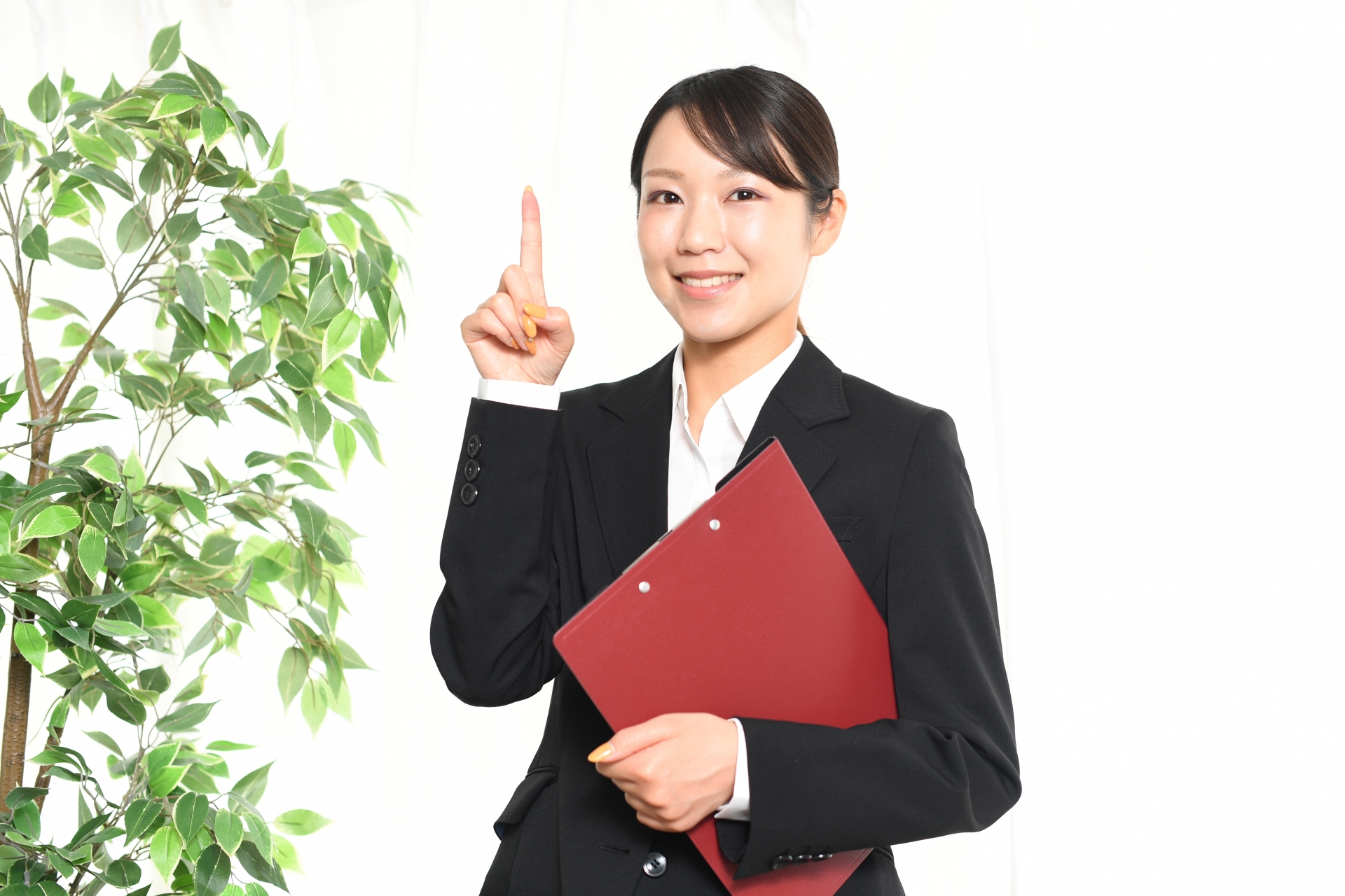人差し指を立てるスーツ姿の女性