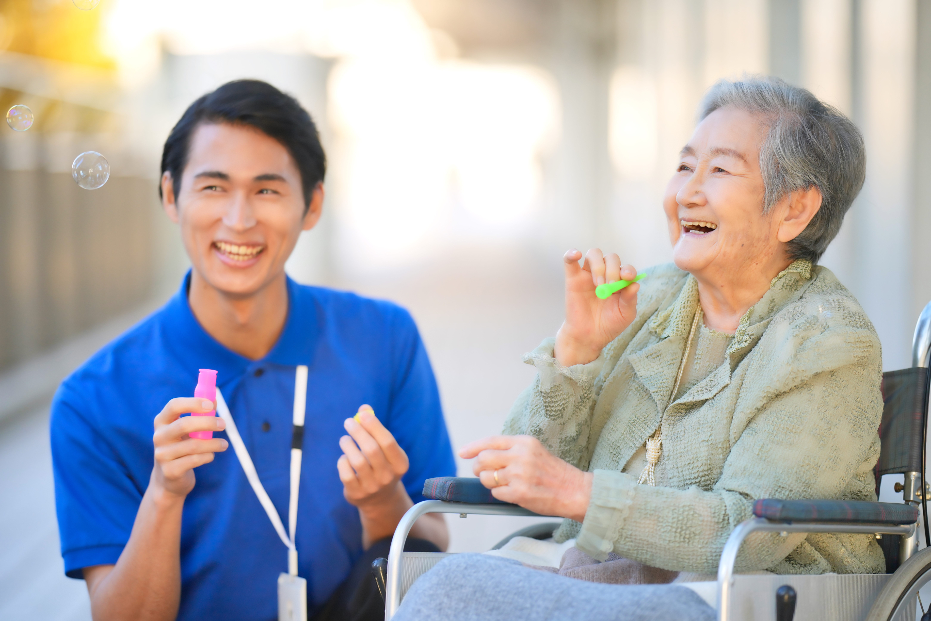 シャボン玉をするおばあちゃんと介護士（車椅子）