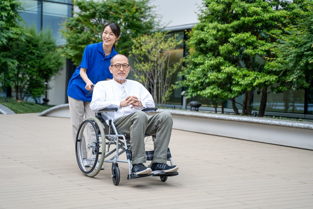 車いすのシニア男性と介護施設スタッフ