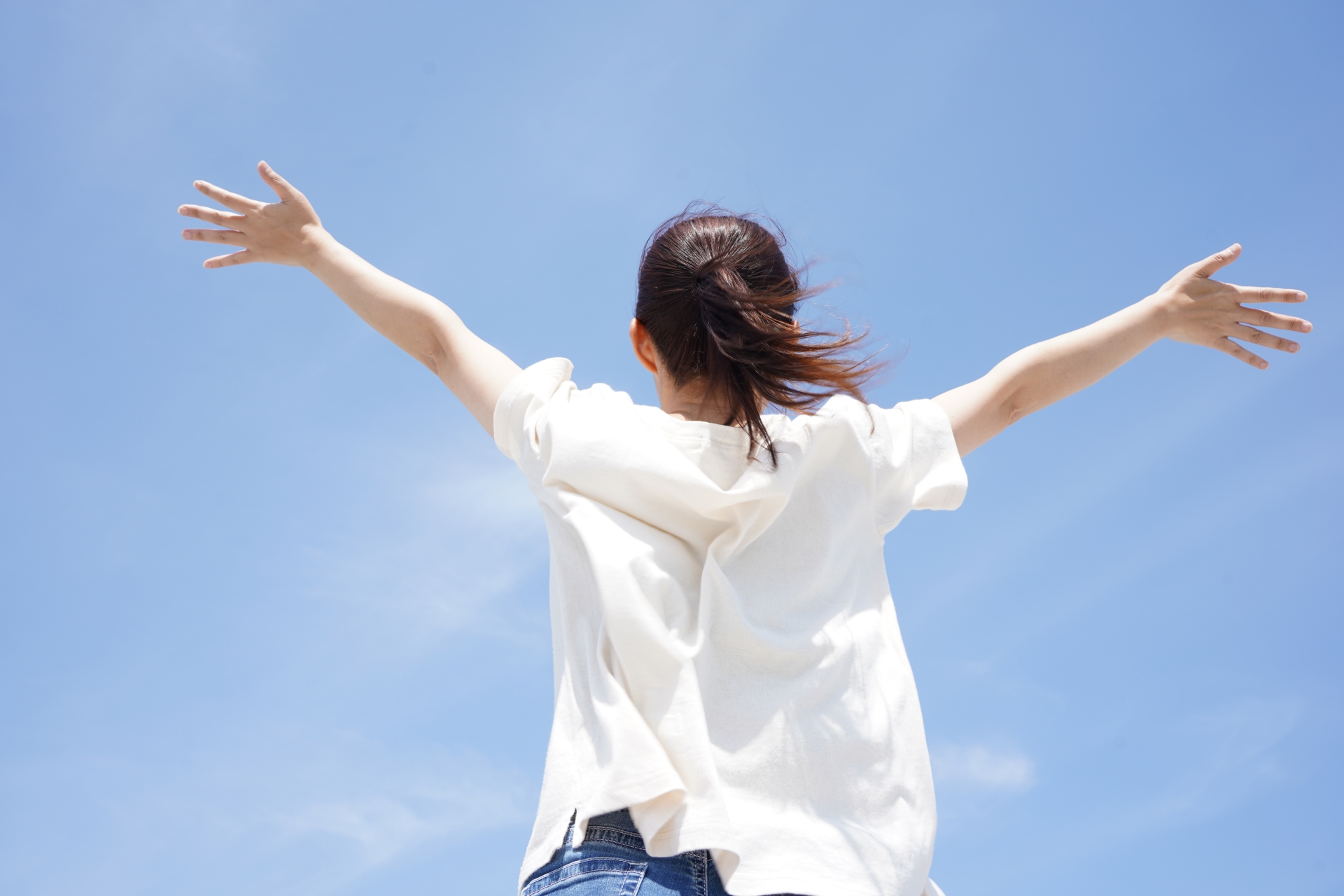 空に向かって両手を広げる人