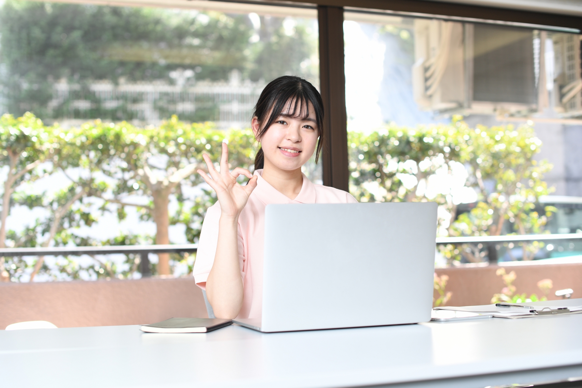 パソコンの前でOKサインをする女性