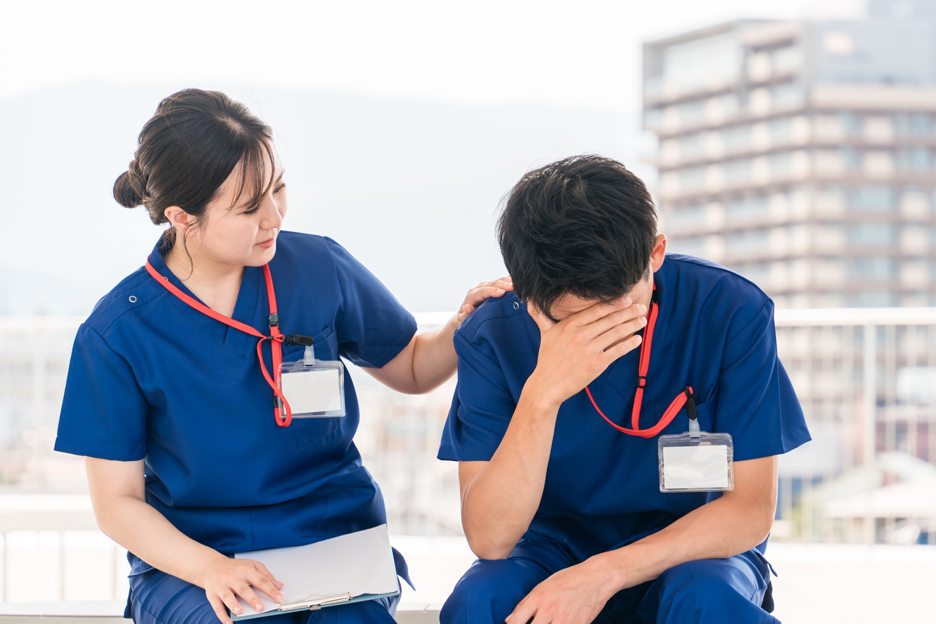 辛そうな男性介護士と心配そうにする女性