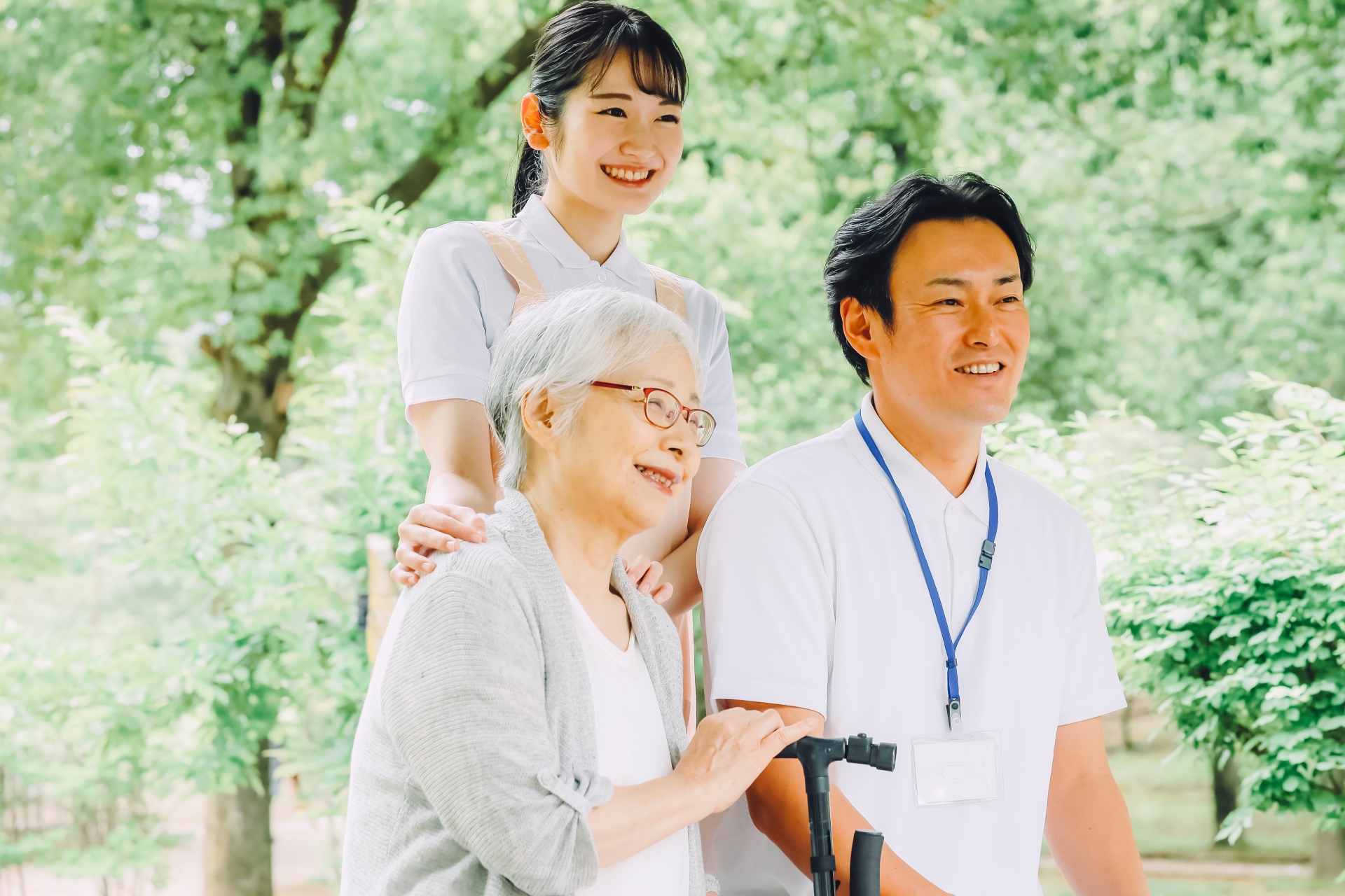 高齢者女性と男女スタッフ(新緑)