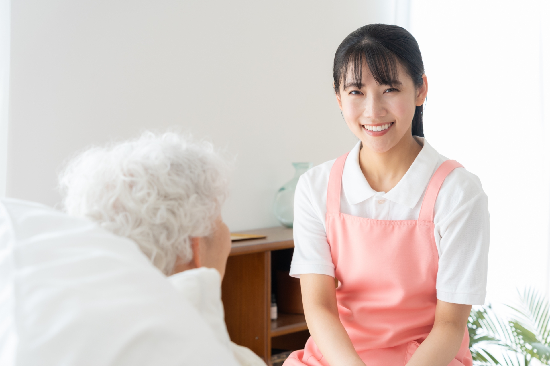 寝ているシニア女性を介護をする介護士