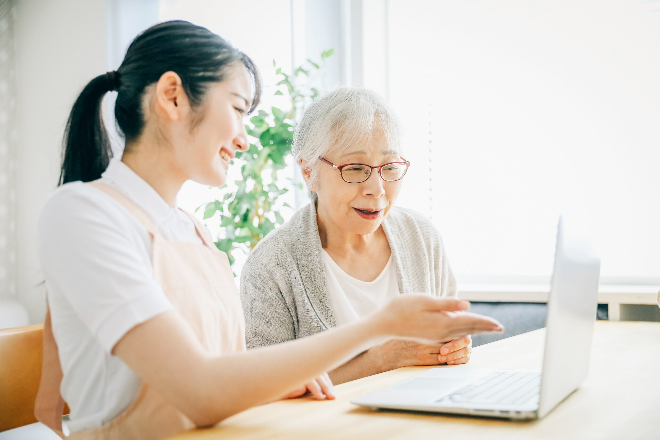 パソコンを使うエプロン姿の女性と高齢者