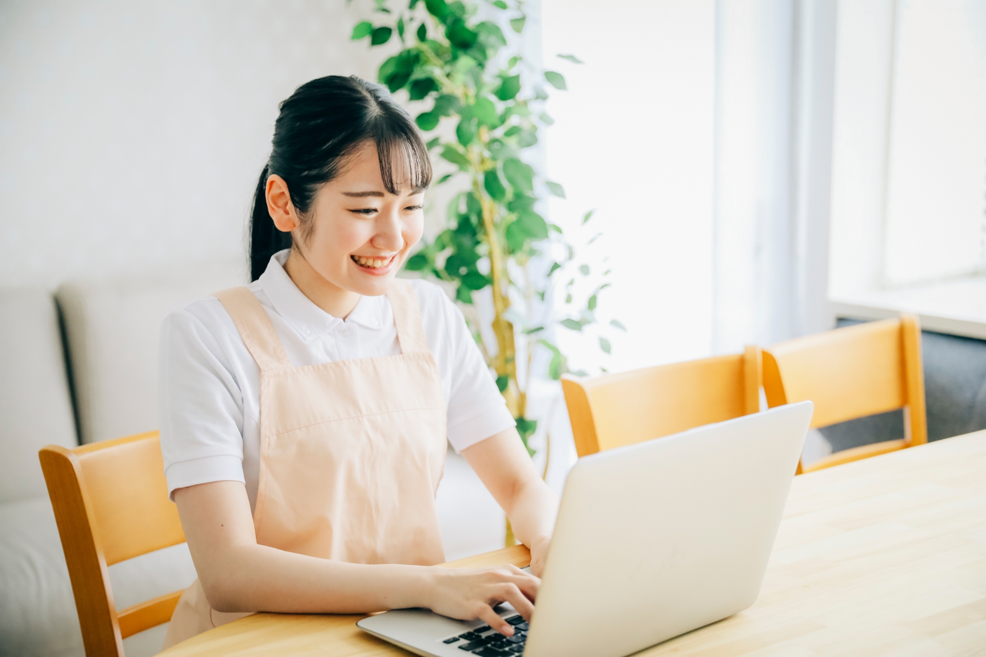 パソコンを使うエプロン姿の女性
