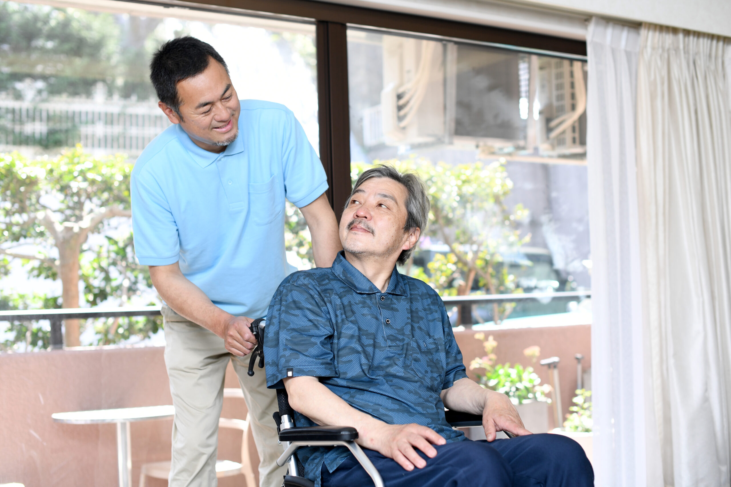 車椅子に乗る高齢者と男性の介護士