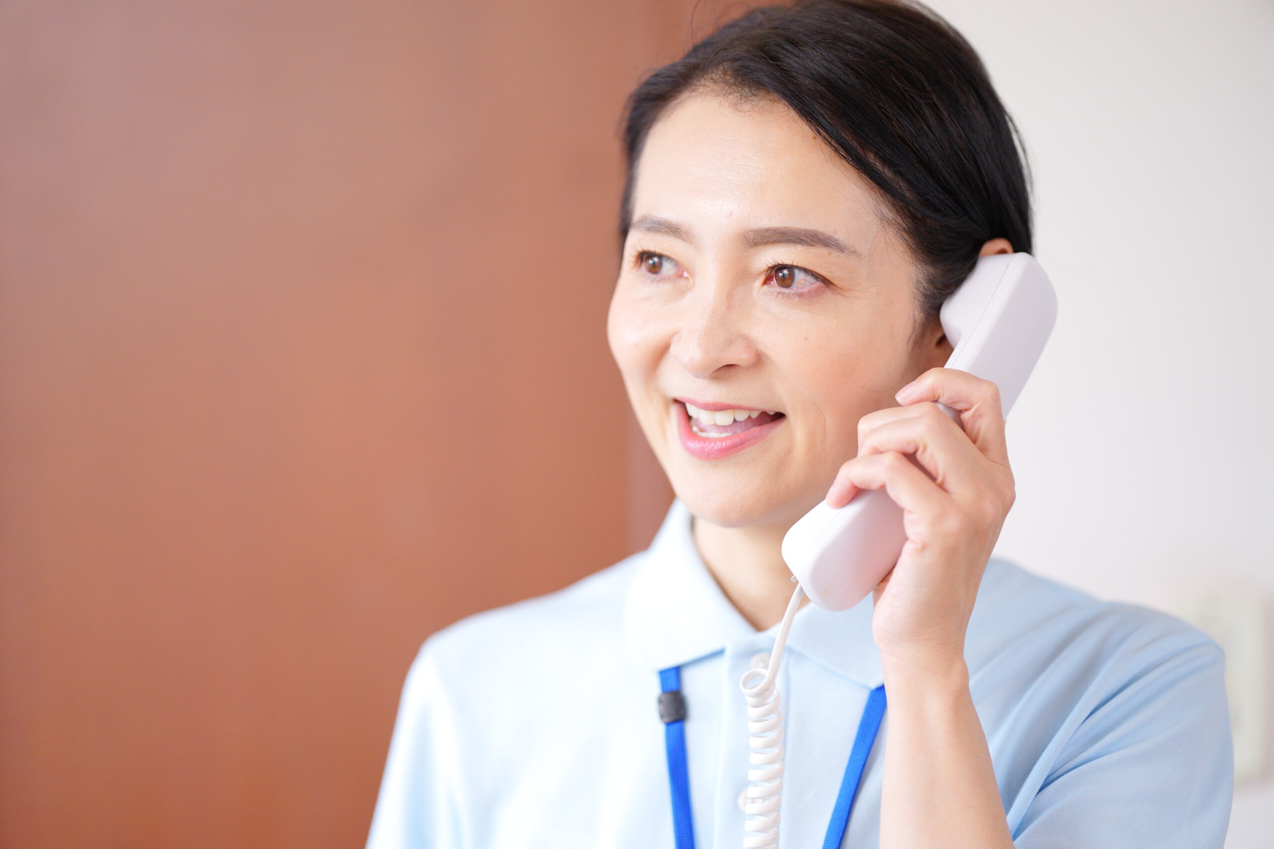 固定電話で話す女性介護士