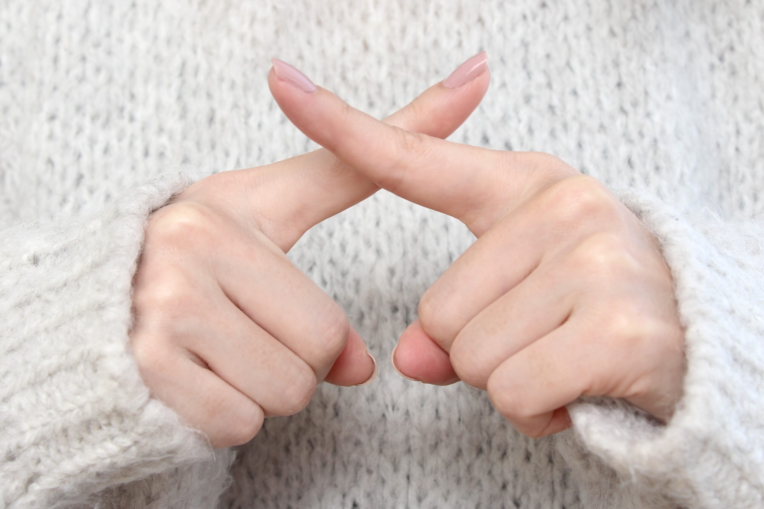 バツポーズの女性の手元