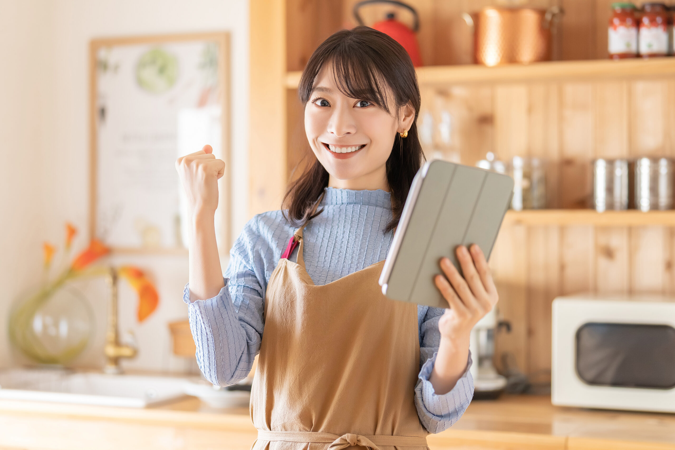 タブレットを見ながら料理をする笑顔の女性