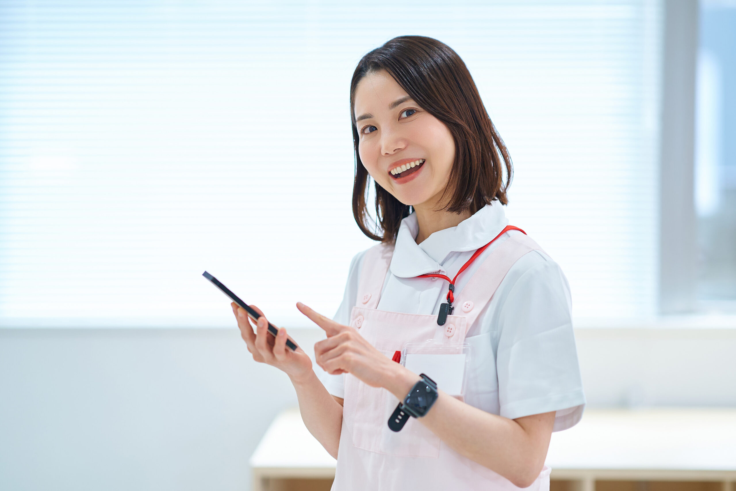 スマホを持つ白衣とエプロン姿の女性