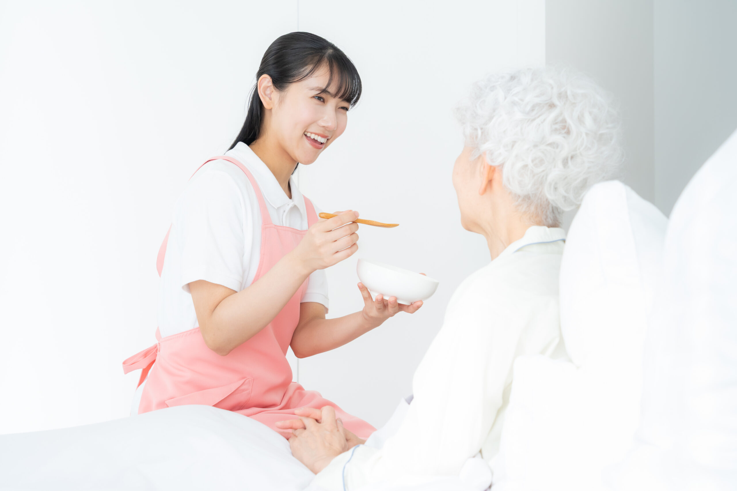 寝ているシニア女性を介護をする介護士