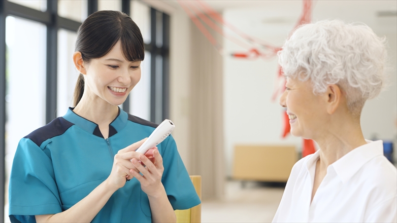 高齢者の体温を測るアジア人介護士