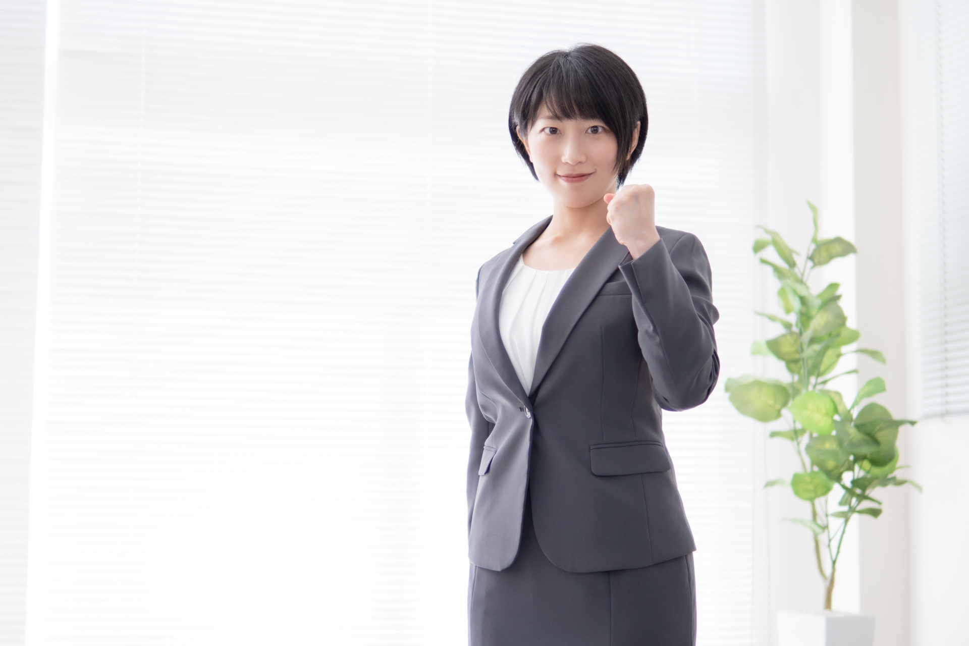 片手でガッツポーズをとるスーツ姿の女性