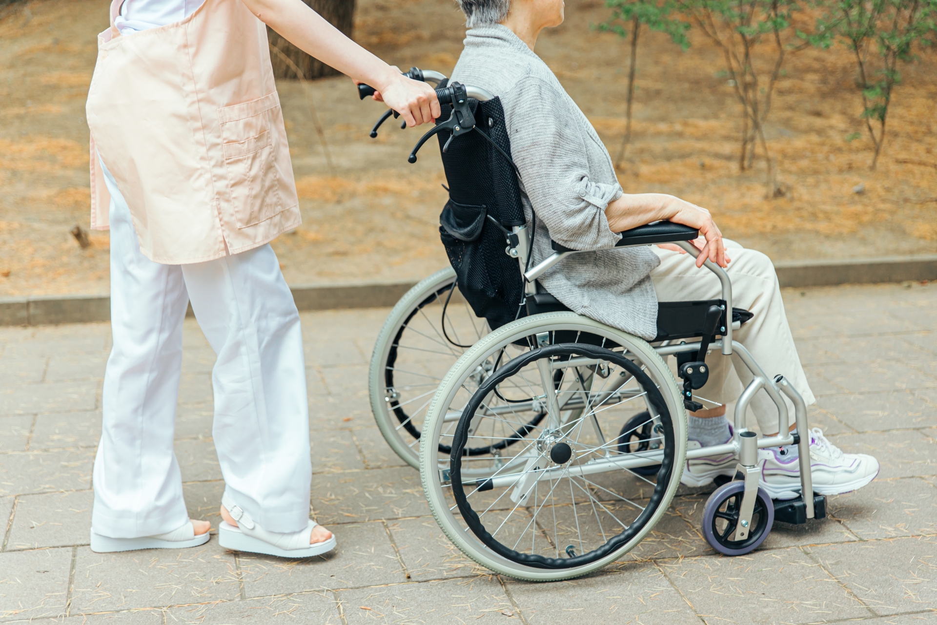 車椅子に乗った高齢者女性と女性スタッフ(横顔)