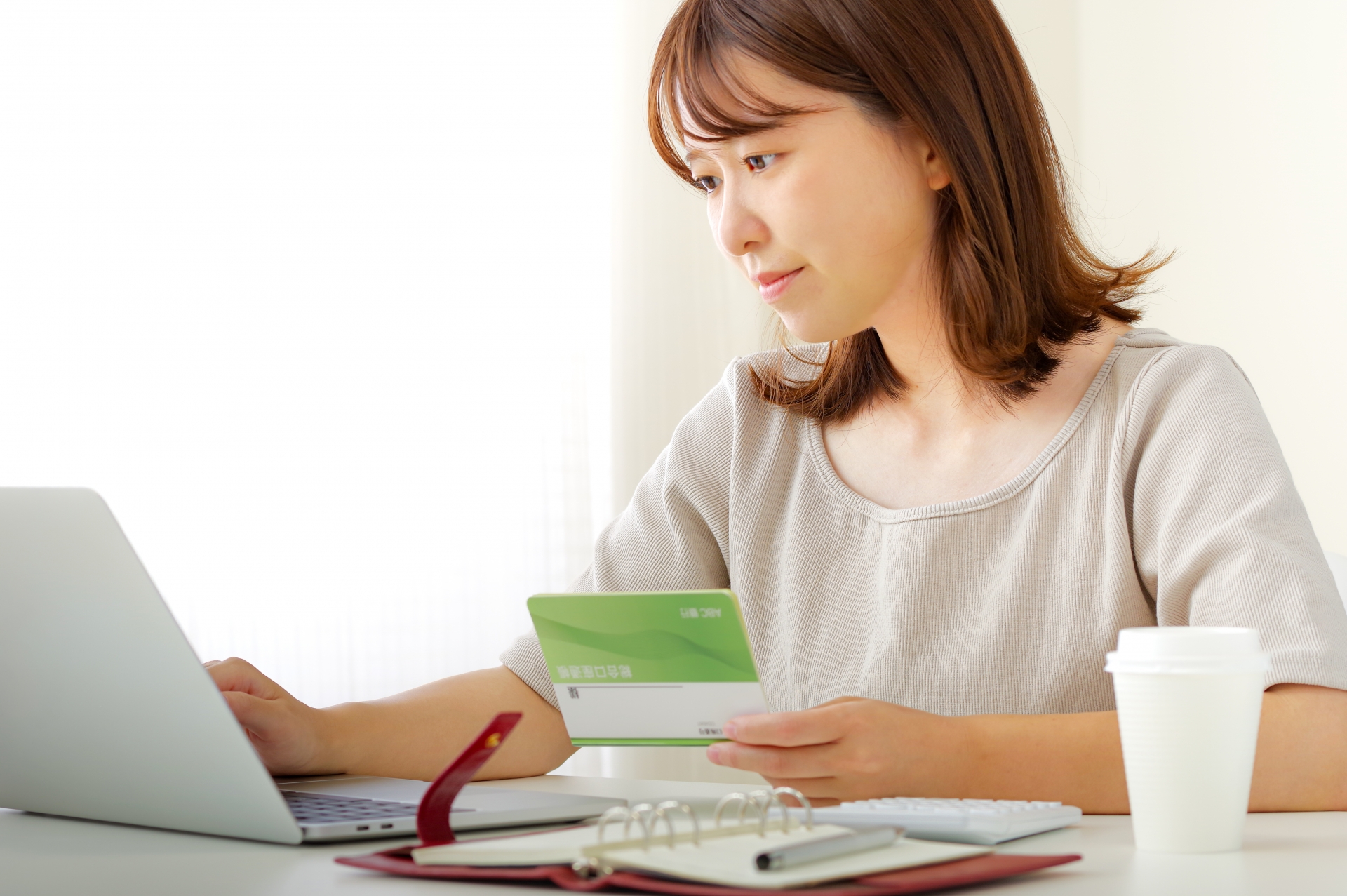 通帳を手にパソコン操作する人