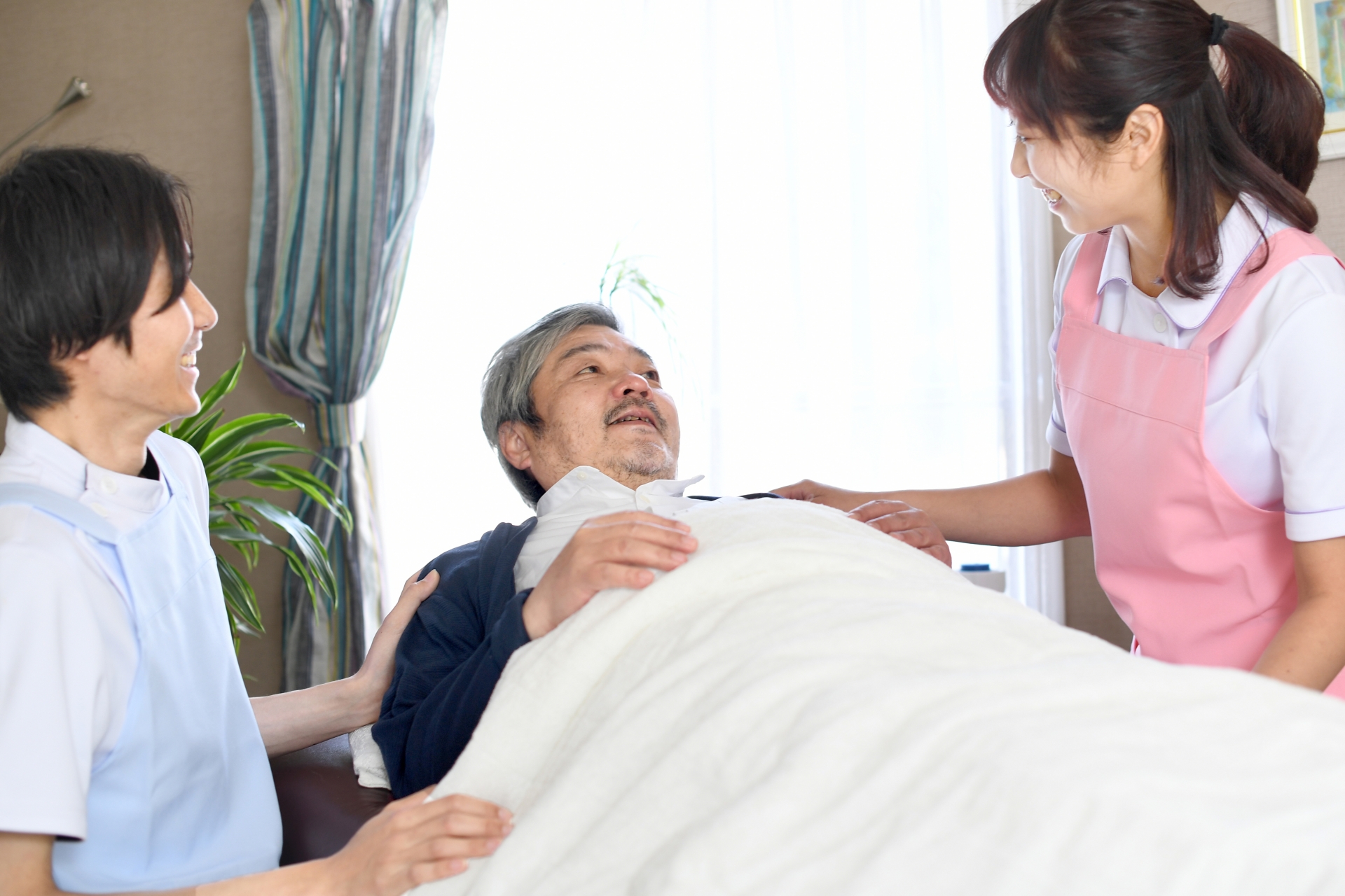 寝たきりのお年寄りと介護士の男女