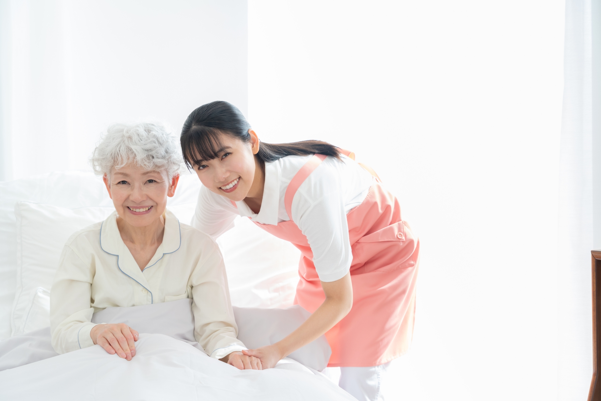 寝ているシニア女性を介護をする介護士