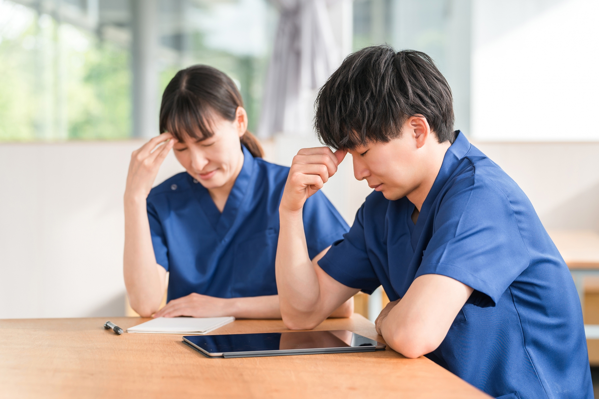 スクラブを着た看護師の男女（過労・疲労）