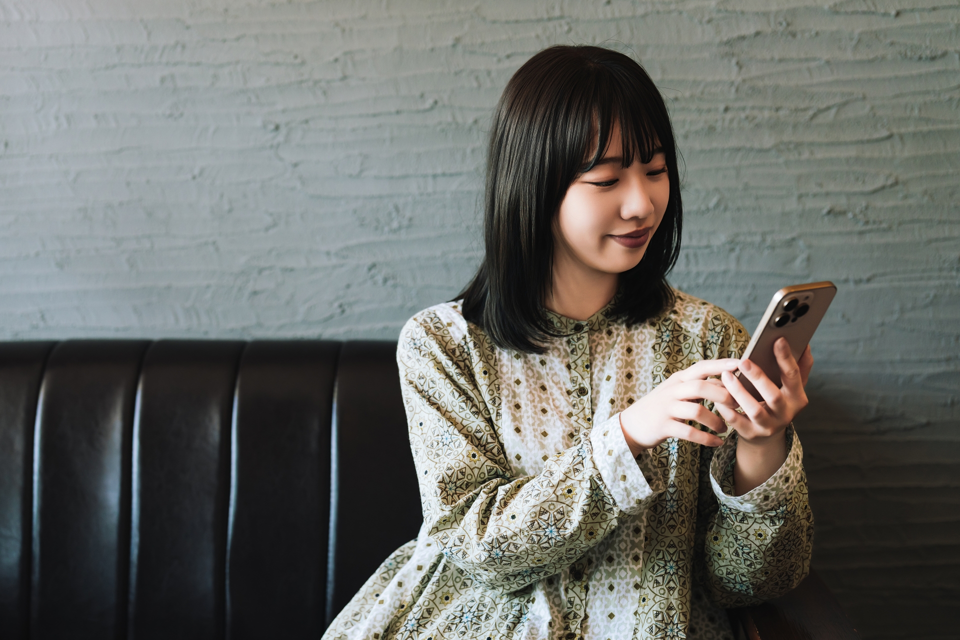 ソファに座ってスマホを使う若い女性