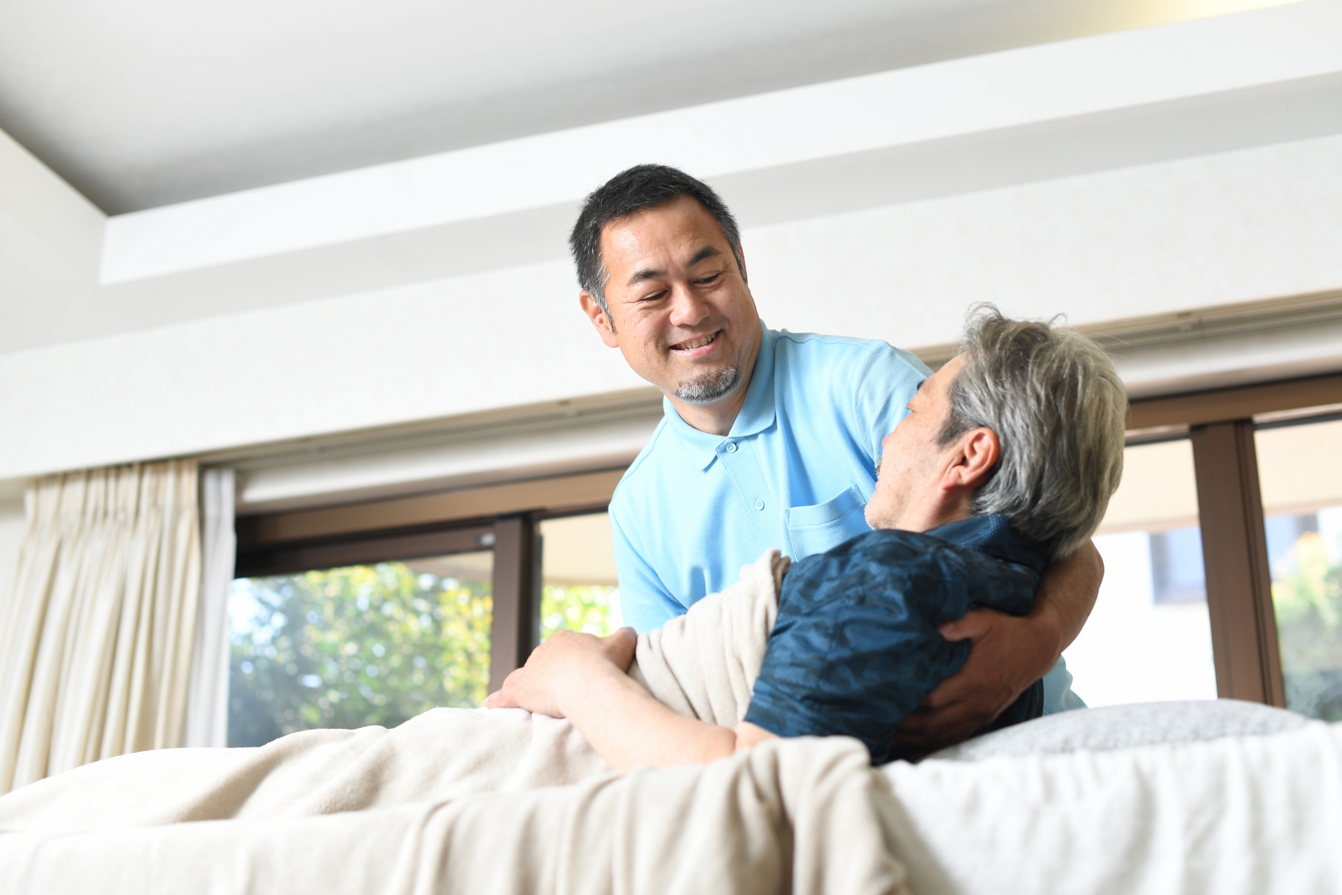 高齢者をベッドで介助する男性介護士