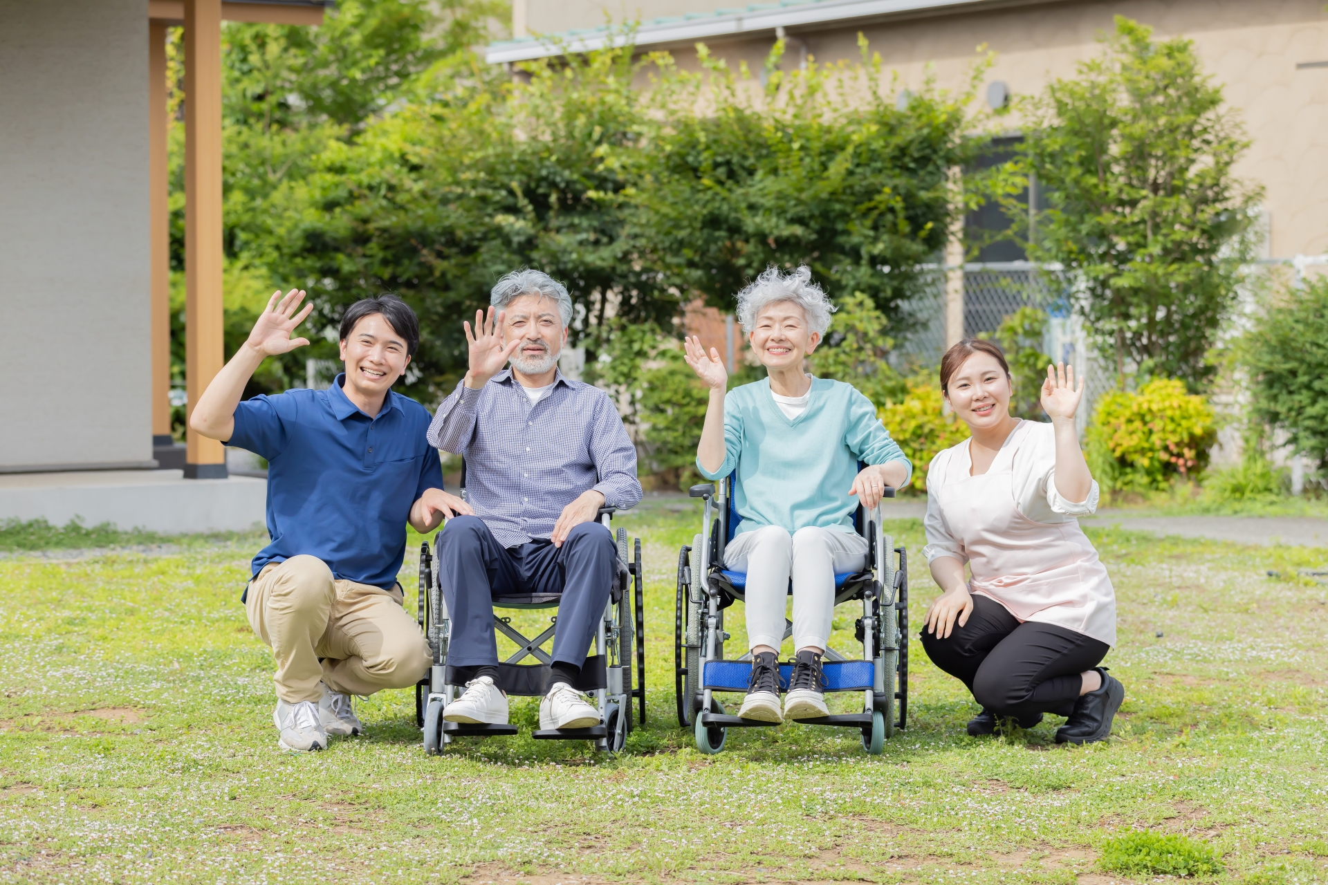 芝生で手を振る車椅子と介護士の人々